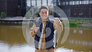 Asian male feeling happy because he caught a fish and keeps it on the hook and looking at the camera. People and fishing