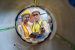 Asian male and female factory worker inspecting quality rolls of metal sheet in factory. Metalwork manufacturing, warehouse of raw