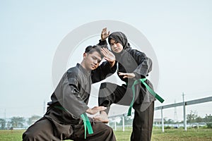 Asian male and female fighters wear pencak silat uniforms with stance formation poses