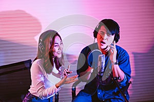 Asian male and a female vocalist singing in the studio in a rehearsal session. Performance and show in the music business.