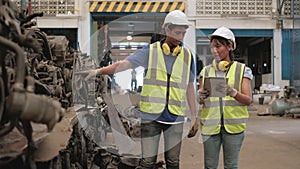 Asian male and female workers in uniforms and helmets, Employee stock check of car spare parts warehouse factory. Using a tablet t