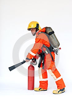 An Asian male firefighter in red protective uniform, mask and helmet with fire extinguisher standing on white background.