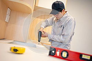 Asian male furniture assembler installing kitchen counter