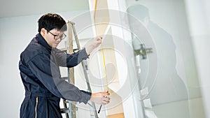 Asian male furniture assembler using tape measure