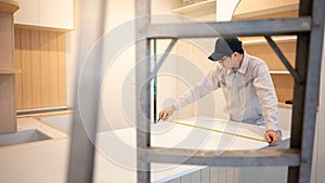 Asian male furniture assembler using tape measure