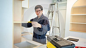 Asian male furniture assembler using tape measure