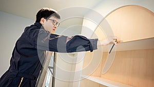 Asian male furniture assembler using tape measure