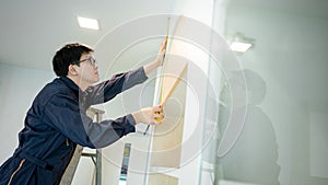 Asian male furniture assembler using tape measure