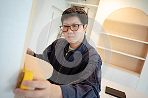 Asian male furniture assembler using tape measure