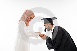 Asian male graduate student wearing toga shaking hands with mother