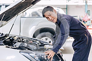 Asian male mechanic garage staff worker car engine service in auto shop happy smiling portrait