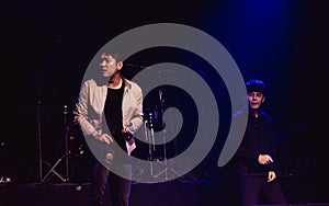 Asian male musical singers singing, celebrating, showing performance on stage in concert or event at night with spot light.