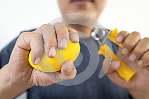 Asian male patient doing hand,finger and wrist exercise with rubber ball and spring hand grip,stretch finger or squeeze with hand