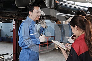 Supervisor engineer is teaching mechanic workers about car repair at a garage.