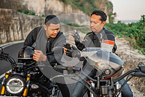 asian male riders sitting motorbike conversating
