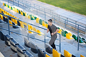 Asian male runner running around modern urban stadium up stairs Cardio morning jog climbing staircase man jogging Outdoor. sport