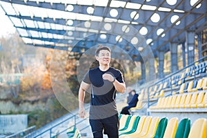 Asian male runner running around modern urban stadium up stairs Cardio morning jog climbing staircase man jogging Outdoor. sport