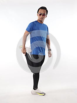 Asian male runner warming up prepararing his body before running workout. stretch his leg muscle, studio full length portrait