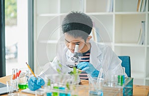 Asian male science students looking through a microscope and tests of plants in the classroom. Learning about scientific