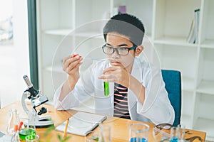 Asian male science students looking through a microscope and tests of plants in the classroom. Learning about scientific