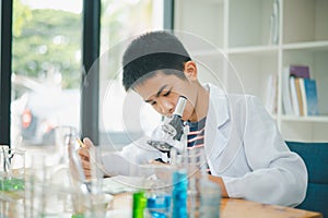 Asian male science students looking through a microscope and tests of plants in the classroom. Learning about scientific