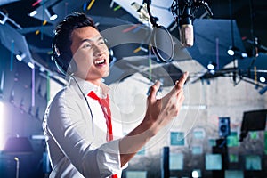 Asian male singer producing song in recording studio