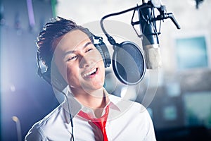 Asian male singer producing song in recording studio