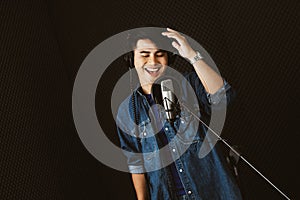 Asian male singer recording songs by using a studio microphone and pop shield on mic with passion in a music recording studio.