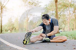Asian male stretching his leg on race track in the park