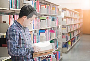 asian male student reading a book in a library, knowledge, education and school concept