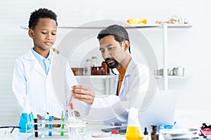 Asian male teacher teaching little african boy in science classroom. Learn about science experiments. in elementary school science