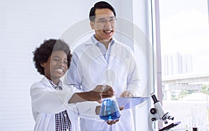 Asian male teacher is teaching science and experiment to African black boy in classroom at school. Education Concept
