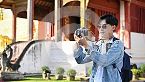 Asian male traveler talking a picture of beautiful ancient Thai-Northern temple by his retro camera