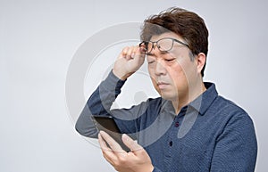 Asian male trying to read something on his mobile phone. poor sight, presbyopia, myopia. photo