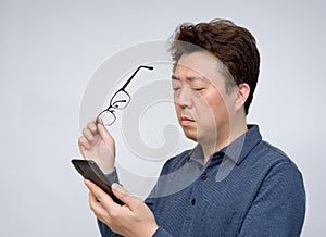 Asian male trying to read something on his mobile phone. poor sight, presbyopia, myopia photo