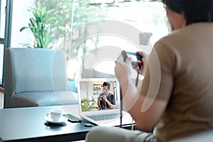 Asian male watching online training workshops for camera function by notebook in the living room