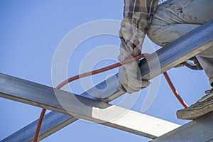 Asian male welder is welding steel beams in process of home renovation. Man worker working for building construction and structure