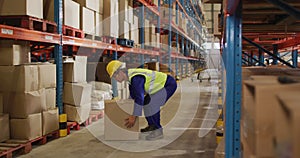 Asian male worker wearing safety suit with helmet and carrying boxes in warehouse