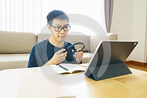 Asian man aged 30-40 years using tablet, watching lesson online course communicate by conference video call from home, e-learning photo