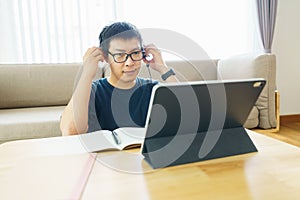 Asian man aged 30-40 years using tablet, watching lesson online course communicate by conference video call from home, e-learning photo