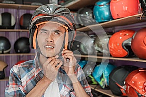 Asian man attaches the strap buckle while wearing the helmet