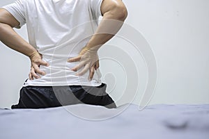 Asian man back pain and sit on bed in bedroom