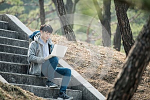 Asian man backpacking using laptop.