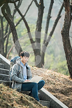 Asian man backpacking using laptop.