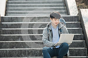 Asian man backpacking using laptop.