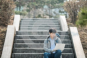 Asian man backpacking using laptop.