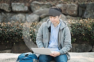 Asian man backpacking using laptop.