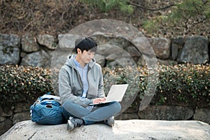 Asian man backpacking using laptop.