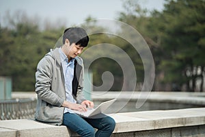 Asian man backpacking using laptop.