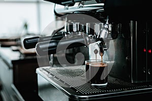 asian man bartender mixing and pouring coffee into cup from coffee machine at counter in small coffee shop